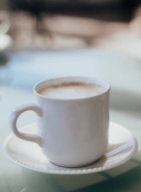 Cam bir masada beyaz bir fincanda servis edilen lezzetli kapuçino..