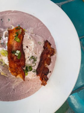 Bir bardak kırmızı şarap, peynir, soğan ve tam buğday ekmeğiyle birlikte Benedict usulü yumurta. Beyaz bir tabakta servis edildi..