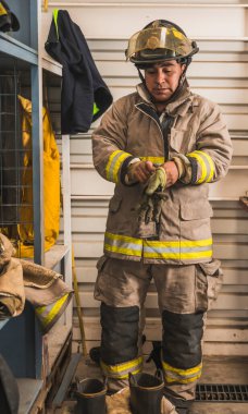 Cesur itfaiyeci asbest kıyafetini, özel botlarını ve diğer ekipmanlarını giyer..