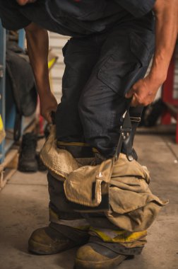 Cesur itfaiyeci asbest kıyafetini, özel botlarını ve diğer ekipmanlarını giyer..