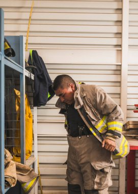 Cesur itfaiyeci asbest kıyafetini, özel botlarını ve diğer ekipmanlarını giyer..