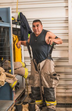 Cesur itfaiyeci asbest kıyafetini, özel botlarını ve diğer ekipmanlarını giyer..