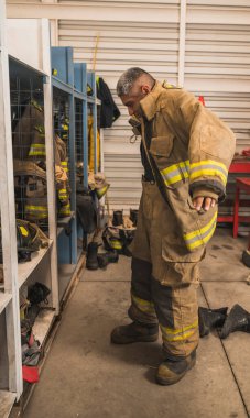 Cesur itfaiyeci asbest kıyafetini, özel botlarını ve diğer ekipmanlarını giyer..