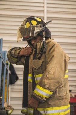 Cesur itfaiyeci asbest kıyafetini, özel botlarını ve diğer ekipmanlarını giyer..