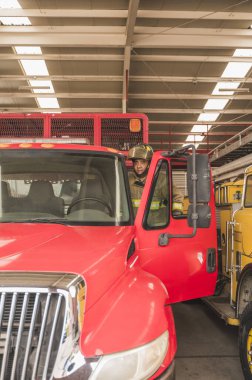 İtfaiyeci. Yangın söndürme çağrısına gitmek için kamyona biniyor..