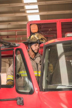 İtfaiyeci. Yangın söndürme çağrısına gitmek için kamyona biniyor..