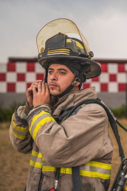 Sapan kökenli cesur itfaiyeci kaskını takıyor ve ayarlıyor. Yangını söndürmeye hazır..
