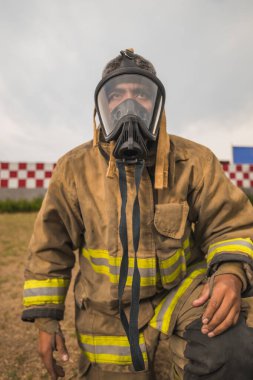 Duman ve gaz maskesi takan cesur itfaiyeci öne eğiliyor..