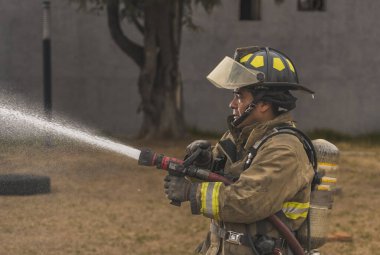 Cesur itfaiyeci, su perdesinin arkasında destansı bir duruşta durup yangını söndürüyor..