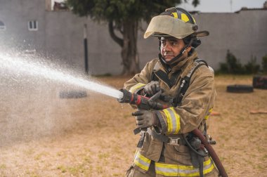 Cesur itfaiyeci, su perdesinin arkasında destansı bir duruşta durup yangını söndürüyor..