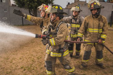 Dört cesur itfaiyeci su perdesinin arkasında durup yangını söndürüyorlar..