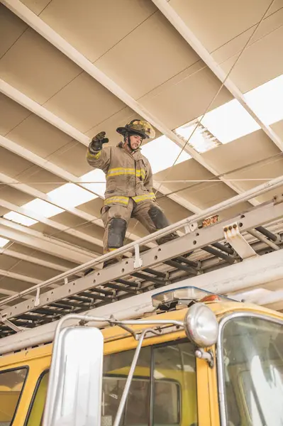 İtfaiyeci, insanları kurtarmak için itfaiye arabasının merdivenlerini çıkıyor..