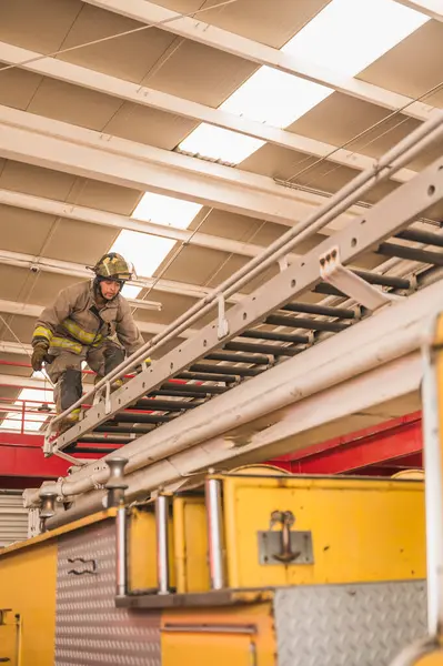 İtfaiyeci, insanları kurtarmak için itfaiye arabasının merdivenlerini çıkıyor..
