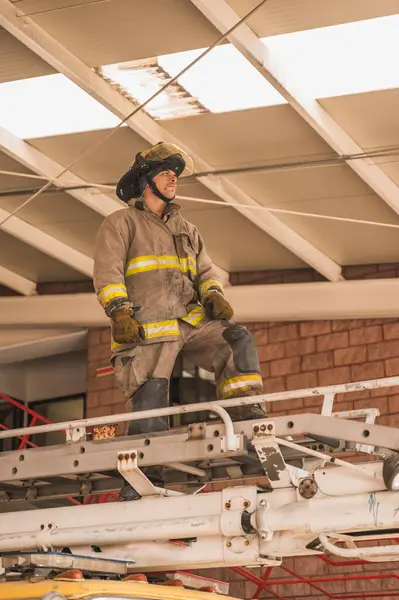 İtfaiyeci, insanları kurtarmak için itfaiye arabasının merdivenlerini çıkıyor..