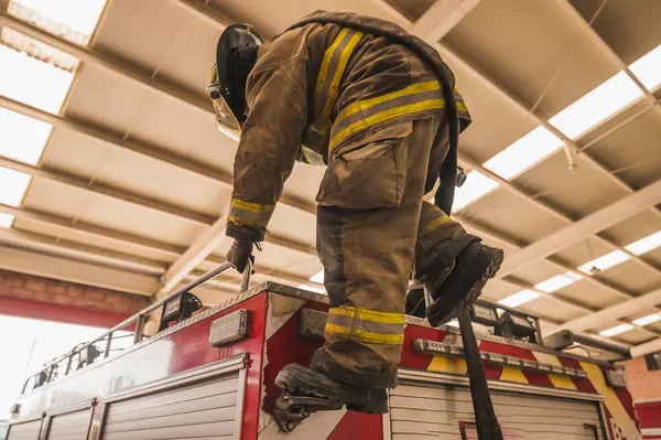 İtfaiyeci, insanları kurtarmak için itfaiye arabasının merdivenlerini çıkıyor..