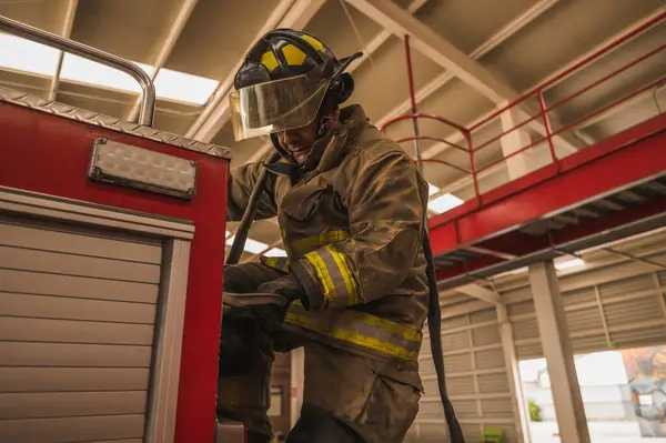 İtfaiyeci, insanları kurtarmak için itfaiye arabasının merdivenlerini çıkıyor..