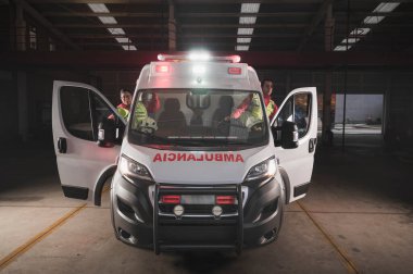 Bir çift Latin erkek ve kadın sağlık görevlisi bir ambulansa binip çağrı sırasında hayat kurtarmaya hazırlanıyorlar..