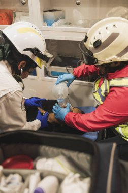 Latin sağlık görevlileri, hava pompasını ve oksijen ölçümünü kullanarak ambulansın içinde bir hastaya ilk yardım sağlıyor..