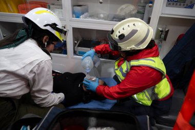 Latin sağlık görevlileri, hava pompasını ve oksijen ölçümünü kullanarak ambulansın içinde bir hastaya ilk yardım sağlıyor..