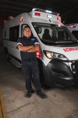 Latin sağlık görevlisi, ambülansın önünde destansı bir poz veriyor, hayat kurtarmaya hazır..