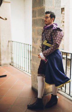 Eski bir malikanenin ikinci katındaki antika korkulukta 1600 'lü yıllardan kalma giysileri olan yakışıklı bir adam..