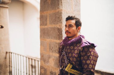 Eski bir malikanenin ikinci katındaki antika korkulukta 1600 'lü yıllardan kalma giysileri olan yakışıklı bir adam..