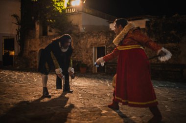 Geleneksel koloni elbiseli İspanyol erkekleri 1600 'lerin geleneksel kasabasında kılıçlarla düello yapıyorlar..
