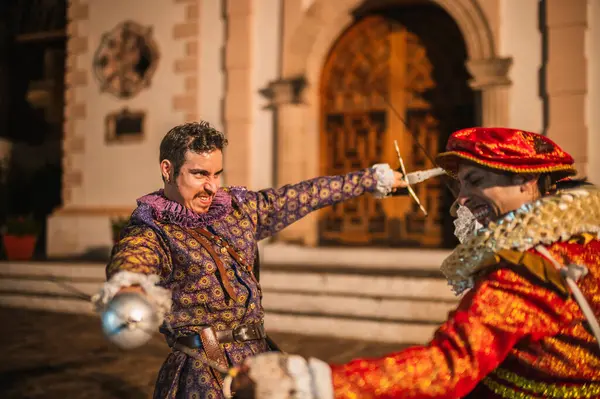 Geleneksel koloni elbiseli İspanyol erkekleri 1600 'lerin geleneksel kasabasında kılıçlarla düello yapıyorlar..