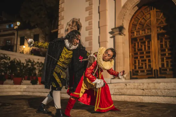Geleneksel koloni elbiseli İspanyol erkekleri 1600 'lerin geleneksel kasabasında kılıçlarla düello yapıyorlar..