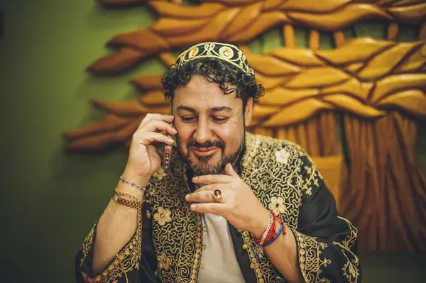 Geleneksel kıyafet giymiş Lübnanlı bir adam Lübnan restoranında kahvesini yudumlarken telefonda gülümsüyor..