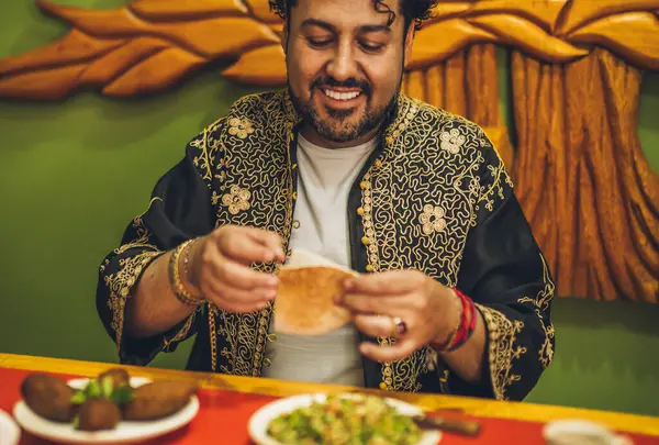 Lübnanlı adam gülümseyerek lezzetli yemeğinin tadını çıkarırken elleri pide ekmeğine dalmış Tabbouleh 'ine eşlik ediyordu..