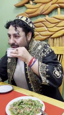 Geleneksel giyinmiş bir Lübnanlı adamın geleneksel bir Lübnan restoranında fincanında Arap kahvesi içtiği dikey 4K video..