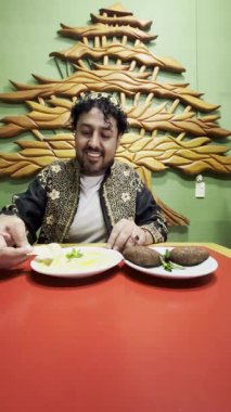Lezzetli geleneksel yemeğinin tadını çıkaran Lübnanlı bir adamın elleri pide ile humusa eşlik ettiği dikey 4K videosu..