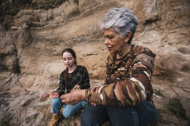 Anne ve kızı ormanda bir öğleden sonranın tadını çıkarıyor, bir uçurumda oturuyor ve ufka bakıyor..