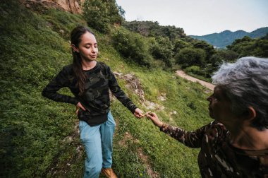 Anne ve kızı yürüyüş kıyafetleri giyip yağmur ormanlarının ortasında bir patika boyunca yürüyorlar..