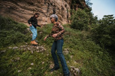 Anne ve kızı yürüyüş kıyafetleri giyip yağmur ormanlarının ortasında bir patika boyunca yürüyorlar..