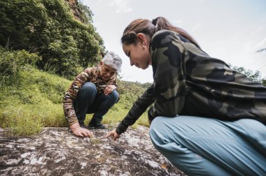 Anne ve kızı ormanda keşfe çıkıyor, bitkileri gözlemliyor.