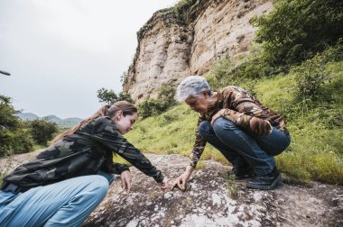Anne ve kızı ormanda keşfe çıkıyor, bitkileri gözlemliyor.