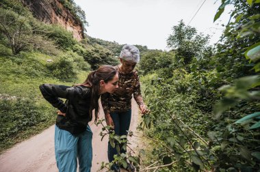 Anne ve kızı ormanda keşfe çıkıyor, bitkileri gözlemliyor.