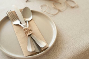 Ev dekorasyonu, doğal yaşam tarzı, ziyafet dekorasyonu, çevre dostu, sonbahar konsepti. Seramik tabak, kağıt peçetedeki metal çatal bıçak seti, kuru lavanta, eko kelimesi masa örtüsündeki iple yazılır..