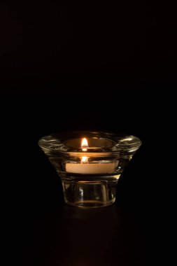 Siyah zemin üzerinde yanan bir mum bulunan cam şamdan. Anma günü, tatil, bilinç kaybı, karanlık, aydınlık kavramı. Metin için yer.