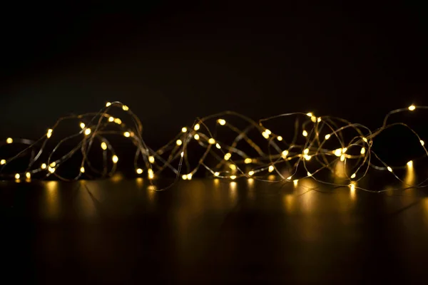 Bulanık altın bokeh ışıklarıyla parıldayan yeni yıl çelengi. Siyah arka plan. Noel, akşam, dilekler, aydınlanma kavramı. Uzayı kopyala Kimse..