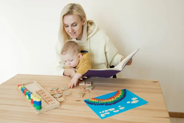 母亲花时间与1岁的婴儿在一起 快乐的妈妈和孩子们和教育玩具坐在一起 早期发展的概念 蒙特梭利方法 室内环境 图库图片