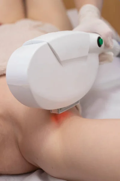 Girl in a beauty salon. Procedure of laser hair removal of hands or removal of age spots. Cosmetologist works with a laser device. The concept of body care, hardware cosmetology.