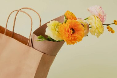 Güzel taze çiçekler, şık dekore edilmiş kese kağıdında küçük bir buket. Açık yeşil arka plan. Uzayı kopyala Hiç kimse. Çiçek, doğum günü hediyesi, sıfır atık hediye konsepti..