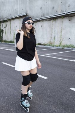 Neşeli kız şehirde paten kayıyor, poz veriyor. Şık kıyafetler, mini etek, güneş gözlüğü. Kafkas ergen kızın keyfi yerinde. Dışarı çıkın. Aktivite, hobi, eğlence, konsept. Gün ışığı. Yaşam tarzı.