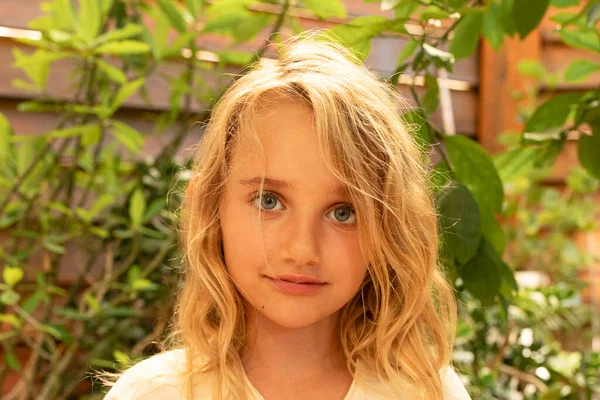 一个可爱可爱的7岁小女孩的画像 她的金发在风中飘扬 温暖的概念 眼神交流笑容满面靠近点外面 图库照片
