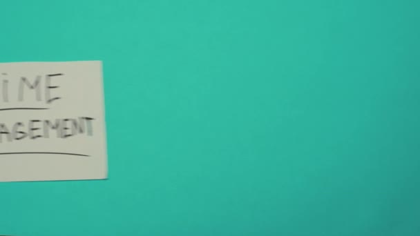 一只手靠在一个坚实的色彩背景上 经过一个贴纸 一张带有文字时间管理的卡片 时间管理概念 截止日期 多项任务 — 图库视频影像