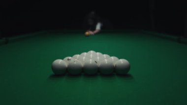 Karanlık bir odada yeşil bir masada bilardo oynamak. Kadın toplara ıstakayla vuruyor ve deliğe vuruyor.