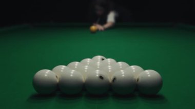Karanlık bir odada yeşil bir masada bilardo oynamak. Kız toplara ıstakayla vuruyor.